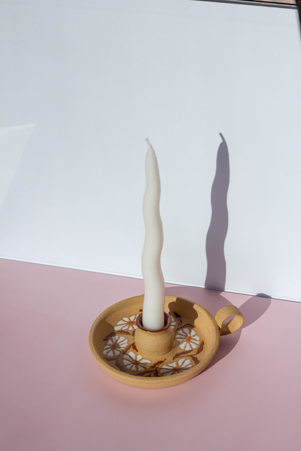 Candle in a decorative holder on a pink and white background