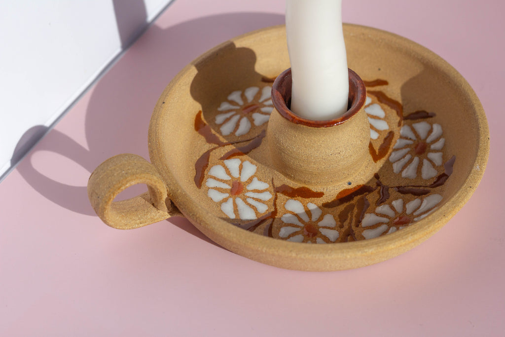 Ceramic candle holder with floral patterns on a pink surface