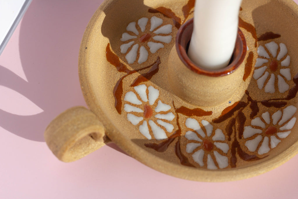Ceramic candle holder with floral design on a pink background